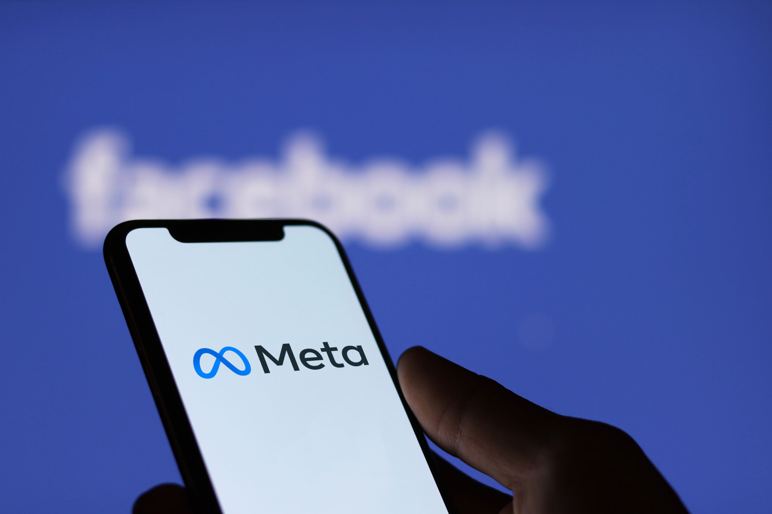 Meta logo on smartphone screen and Facebook logo background