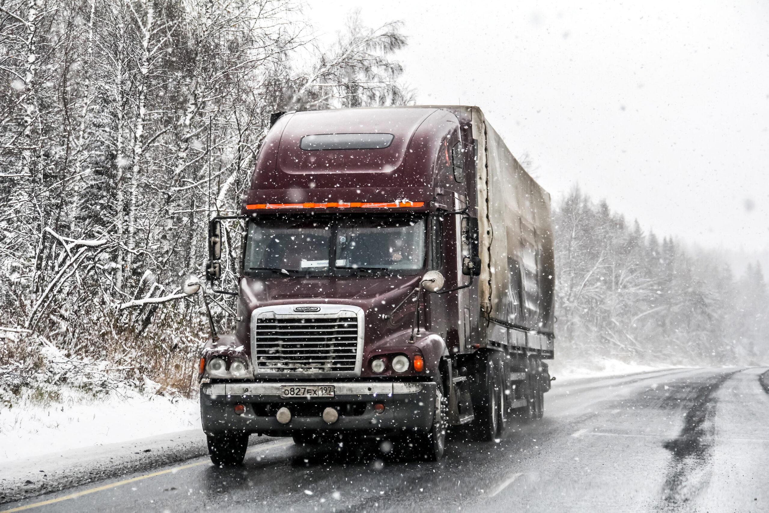 Semi-trailer truck Freightliner Century Class at the interurban freeway during a heavy snowfall.
