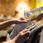 Close up of woman hand choosing shirt off a rack.