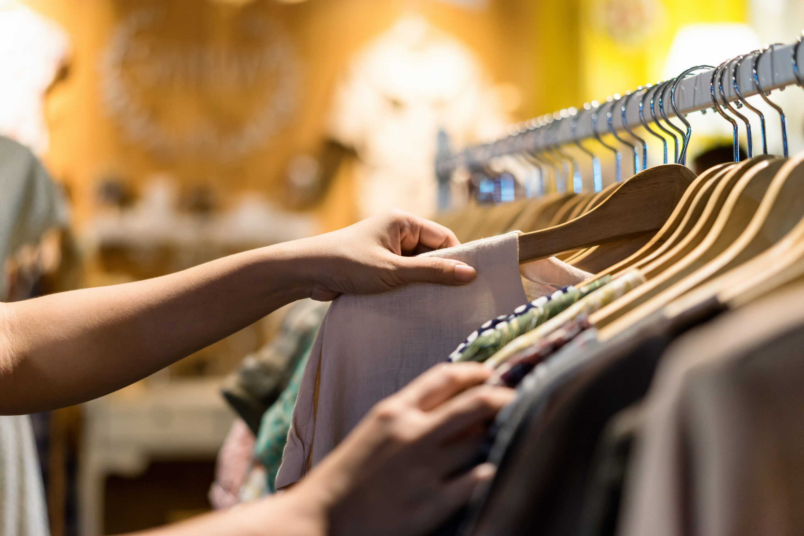 Close up of woman hand choosing shirt off a rack.