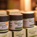 Shelves filled with various skin care products showcasing cleansing and purifying balms in a cozy wellness shop setting.