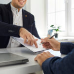 Two people make a business deal and sign a contract agreement in the office.