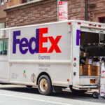 Packages in a FedEx truck with open door, parked on a street downtown