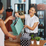 Cropped shot of a young store owner handing a parcel to a customer over the counter