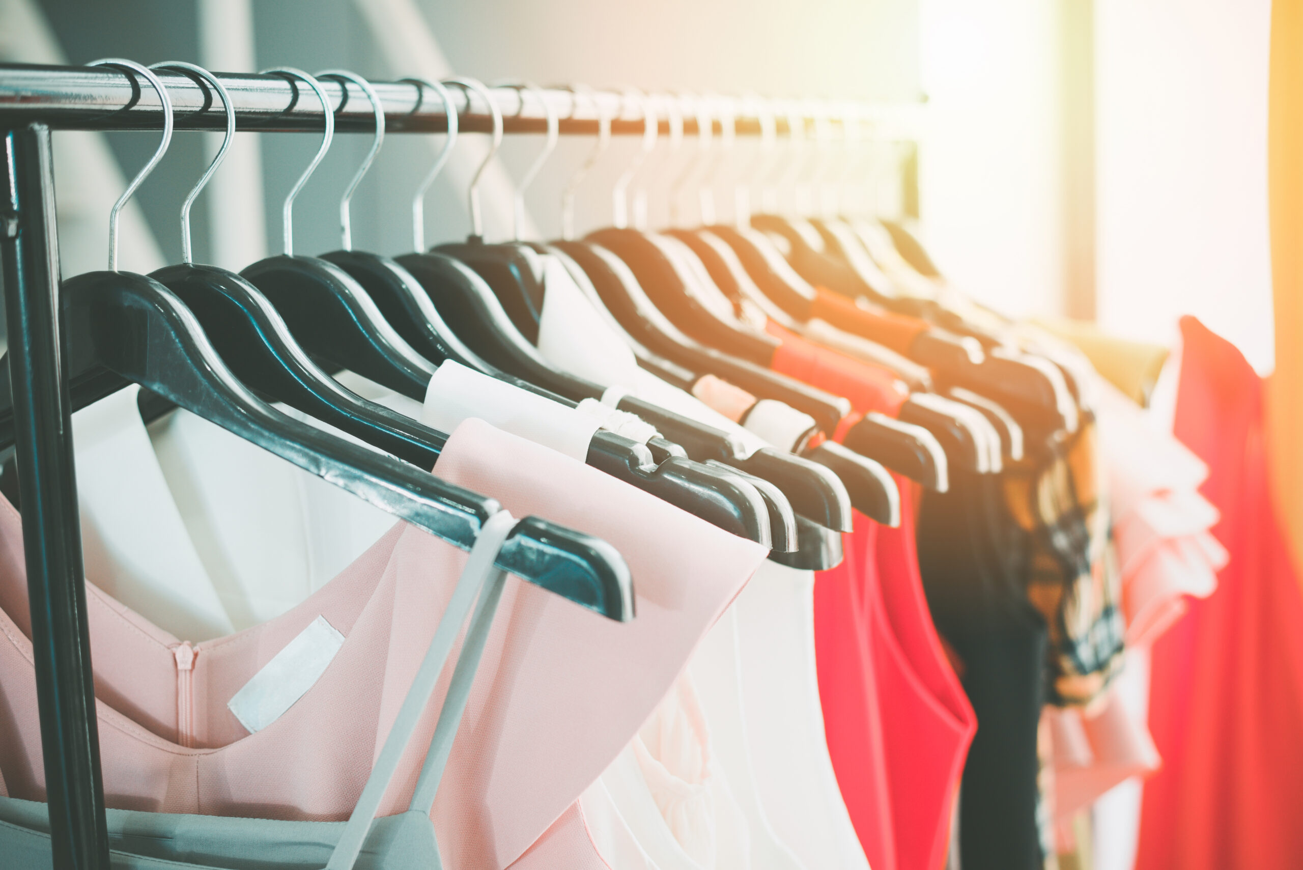 Woman fashion clothes of different colors clothing on hangers on rack.