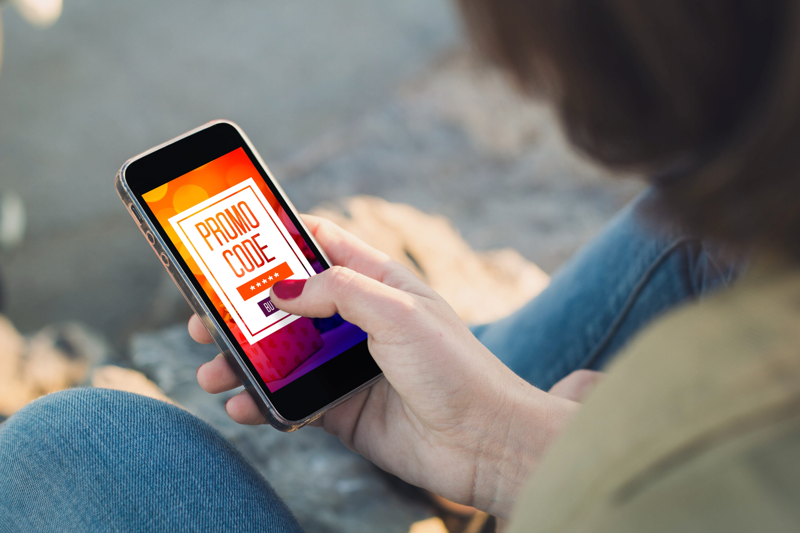 Woman holding a smartphone and buys using a promo code.