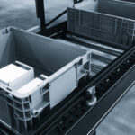 Conveyor belt with two empty plastic containers. Gray containers placed on the conveyor belt.