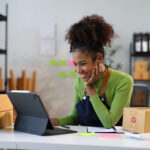 Young woman business owner using digital tablet checking ecommerce orders