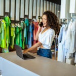 Smiling designer contacts client about online order in fashion shop.