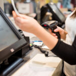 Young woman hand doing process payment on a touchscreen cash register