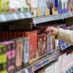Customer hand picking box of chocolates from store shelf.