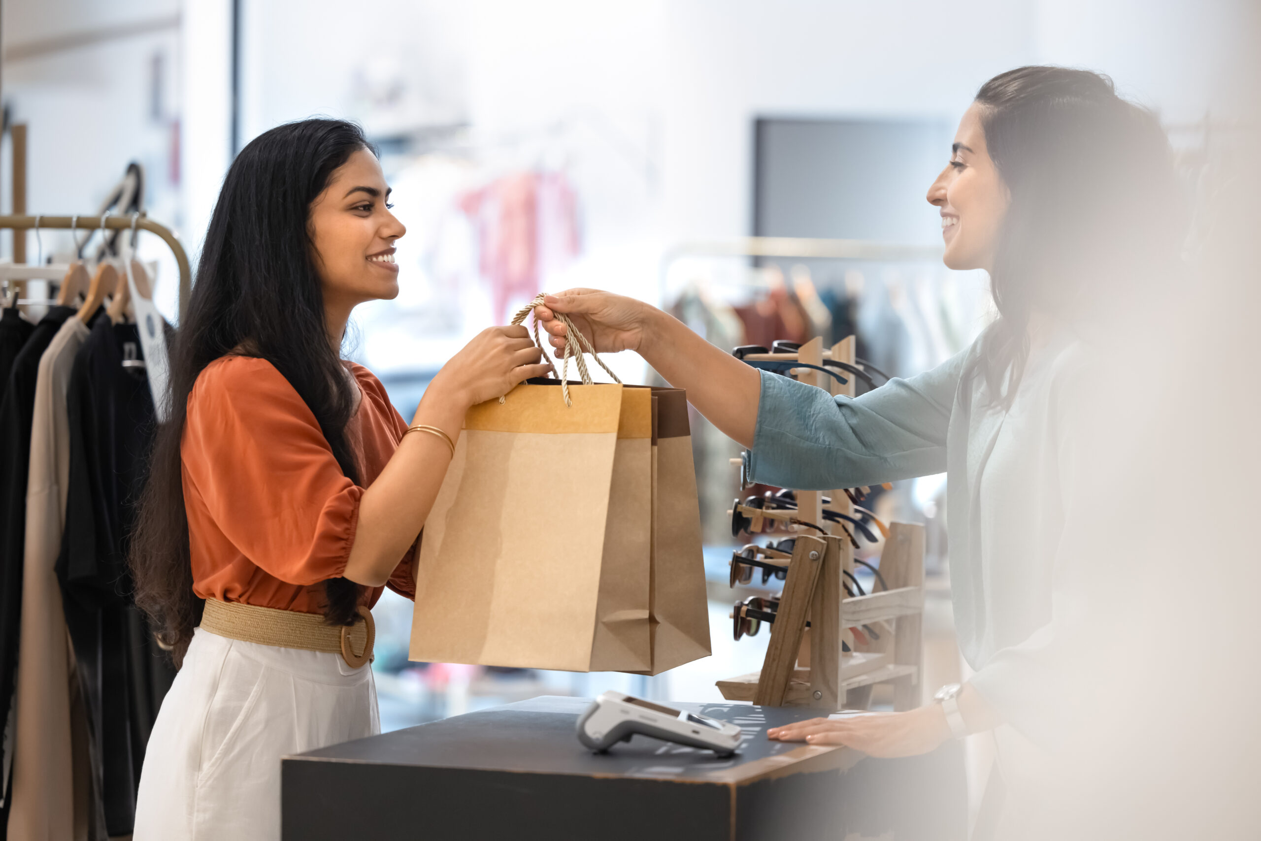Happy customer receives shopping bags at checkout desk