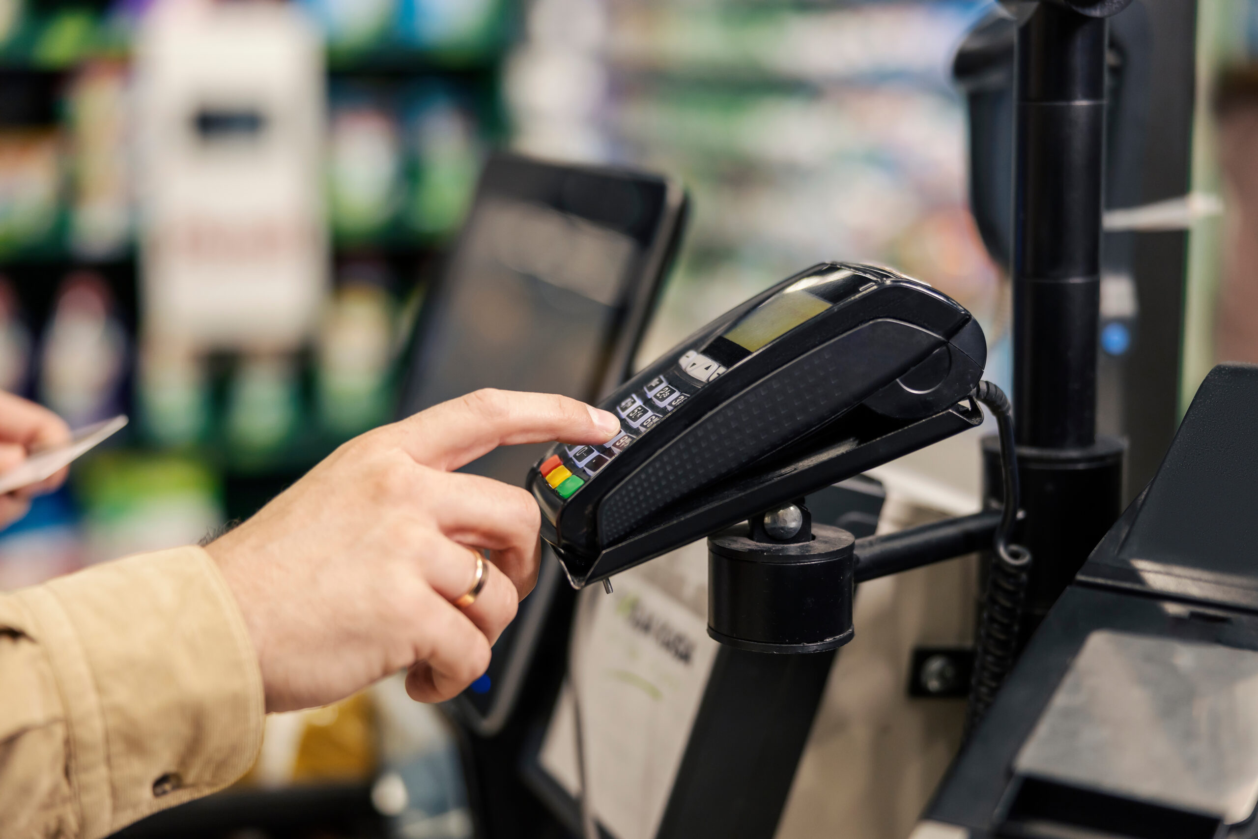 Male's hand entering credit card code at supermarket on pos terminal at self-service checkout.