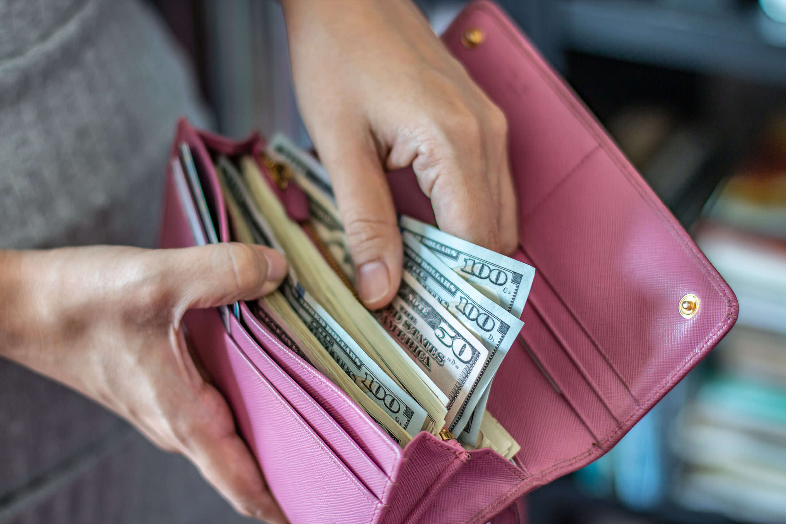 Woman taking out US dollar bills from her pocket wallet