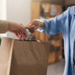 Hands, paper bag and people in boutique
