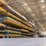 Low-angle view of organized stacks of lumber and pressure-treated wood boards stored on heavy-duty cantilever racks inside a large warehouse store